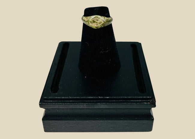 Authentic Roman bronze signet ring, circa 100–300 CE, with oval bezel engraved with geometric intaglio diamond motif, slender tapered band, and rich green patina from centuries of burial, used for sealing documents and personal identity.