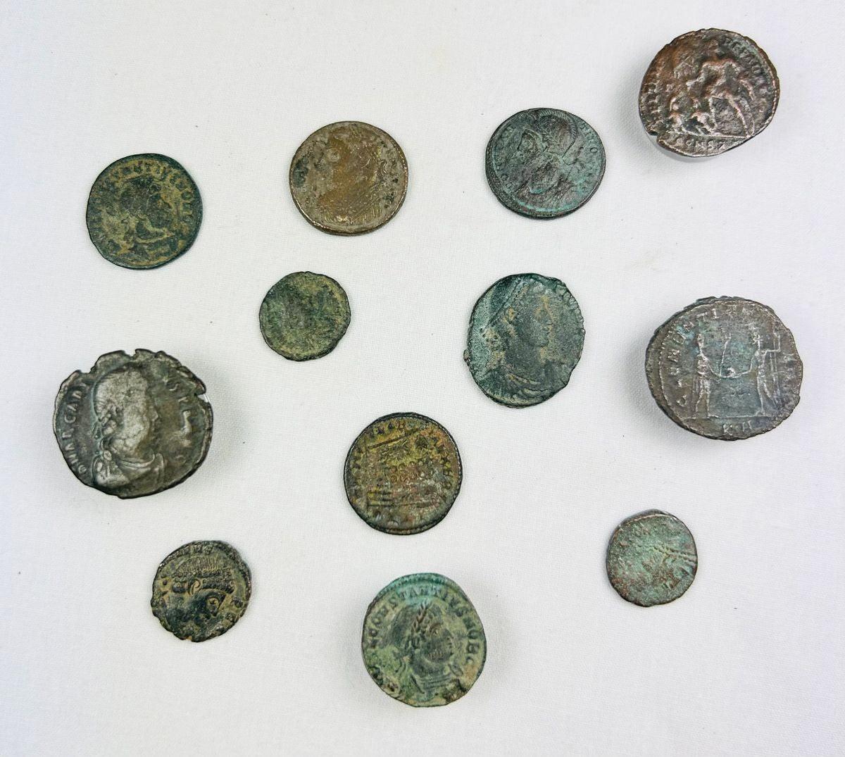 Collection of 12 ancient Roman bronze coins, varying in size and condition, featuring worn imperial busts and reverse imagery; authentic hoard of currency from the Roman Empire with patinated surfaces and archaeological character.