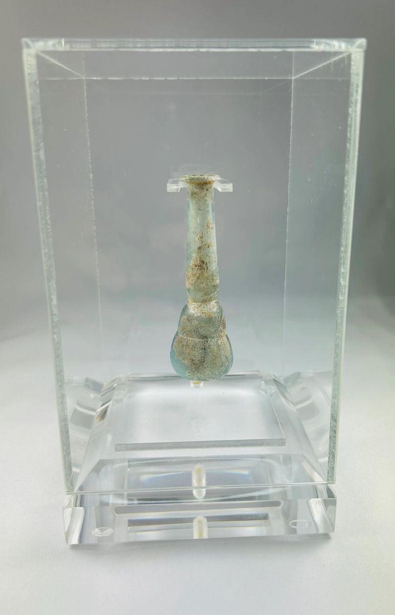 Ancient Roman pale turquoise blown glass balsamarium, 2nd–3rd Century CE. Double-gourd body with tapering neck and outfolded lip, featuring natural iridescent patina. Hand-blown vessel used for perfumes, ointments, and luxury grooming, reflecting Roman craftsmanship, refinement, and elite culture.