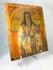 Angled view of an 18th-century Russian Orthodox icon showing a saint holding a Gospel book, hand-painted on an aged wooden panel.