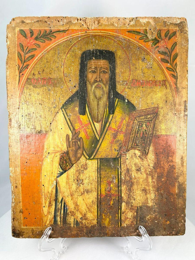 Antique 18th-century Russian Orthodox icon, hand-painted in tempera with gold leaf, depicting a saint in blessing pose with Gospel book, Cyrillic inscription, and floral motifs. Provincial workshop devotional panel with historic patina.