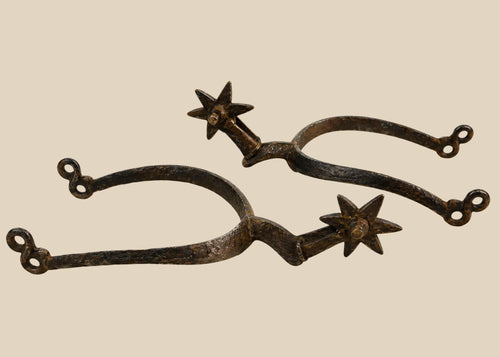 Late 16th–early 17th-century German Saxon spurs forged in iron/steel with large six-pointed rowels, curved frame with high rounded ridge, short hooked shanks with double eye terminals, patinated surfaces, reflecting Renaissance equestrian craftsmanship.