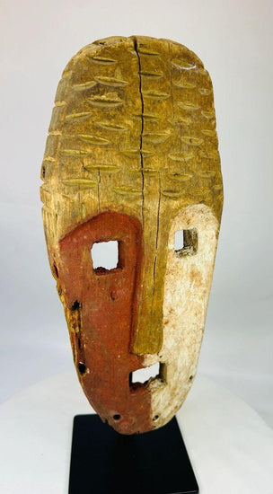 Papua New Guinea Sepik River tribal mask, hand-carved hardwood with red ochre and lime pigments, dual-colored face, circa 1900–1940.