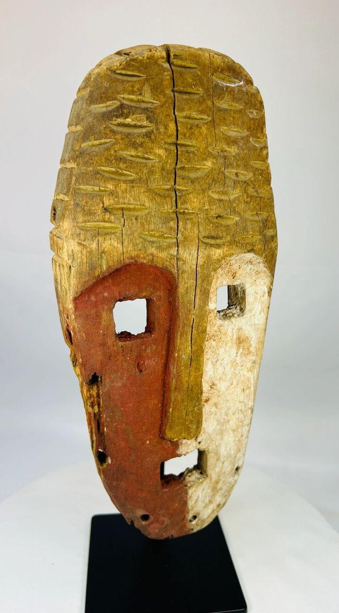 Papua New Guinea Sepik River tribal mask, hand-carved hardwood with red ochre and lime pigments, dual-colored face, circa 1900–1940.