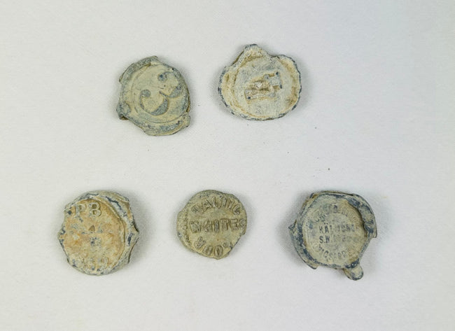 Marine-encrusted lead seals once used to identify bags and bales of traded goods