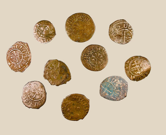 Collection of ten medieval Crusader bronze coins from the 11th–13th century AD, each featuring worn but visible Christian crosses and medieval inscriptions, patinated surfaces in brown and green tones, laid out on a white background, representing numismatic relics from the Crusader states.