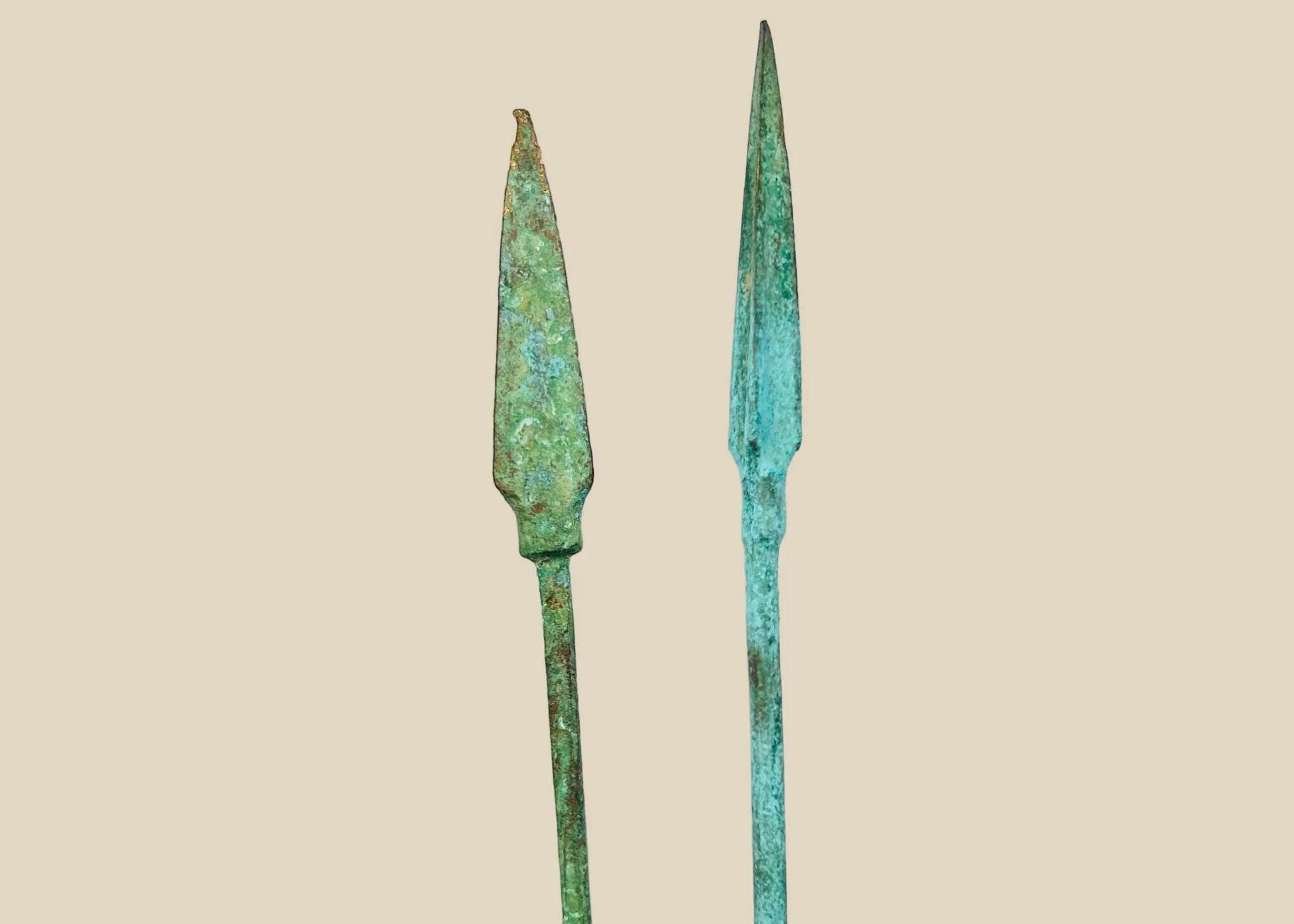 Ancient bronze spearheads with leaf-shaped tapered forms and rich green patina, mounted on black display stands, dating to the Bronze or Iron Age (2nd–1st millennium BCE).