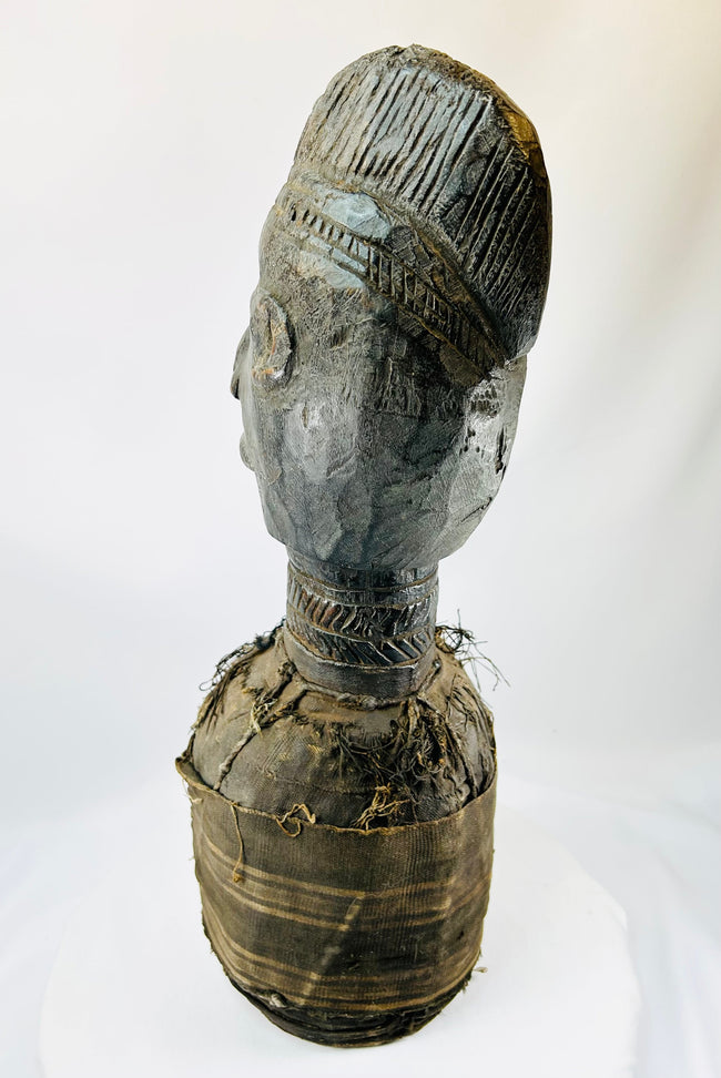 Central or West African carved wooden figure with elongated face and preserved decorative fibers