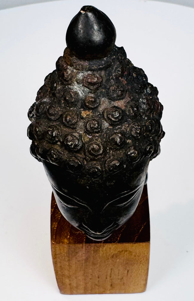 Antique Southeast Asian Buddhist artifact featuring a serene Buddha head with rich dark patina