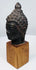 Antique bronze Buddha head with serene expression, closed eyes, and detailed hair curls