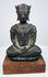 Bronze Buddha statue with a calm expression, winged crown ornaments, and lighter surface wear across its dark patina.