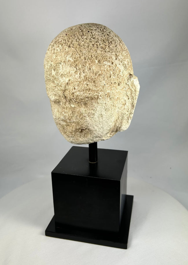 Ancient Southeast Asian stone Buddha sculpture, 13th–14th century head fragment with calm features, carved in Burma or Thailand, displayed on stand.