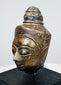 Antique Buddha head with half-closed eyes, slender nose, and detailed crown ornamentation