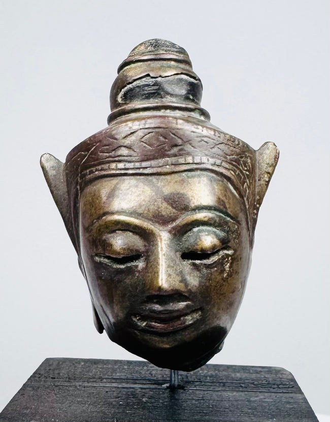 Antique Southeast Asian Buddha sculpture with meditative expression and decorative headdress
