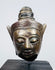 Antique Southeast Asian Buddha sculpture with meditative expression and decorative headdress