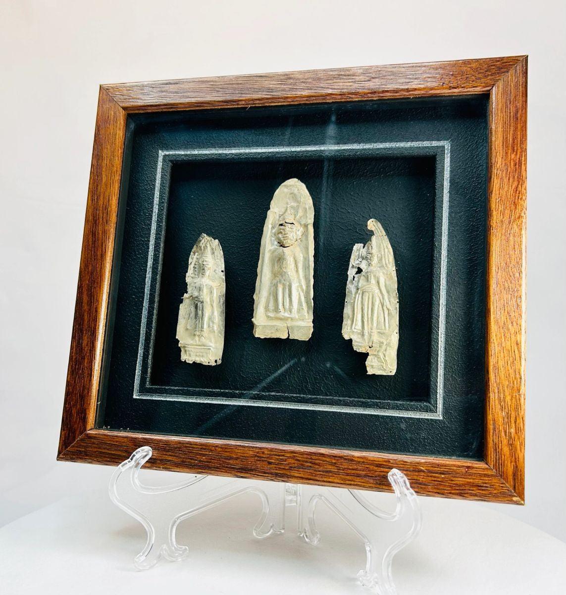 Framed set of three antique cast metal votive plaques from Cambodia or Thailand, 16th–17th Century CE. Central plaque depicts a seated Buddha in meditation, flanked by attendant or deity figures, with intricate engraved details. Mounted on a custom wooden frame, showcasing devotional artistry and Theravāda Buddhist iconography.