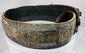 Side view of an antique Jewish ceremonial bridal belt showing its layered brass fittings, gemstone settings, and aged surface wear.