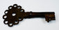 Antique Spanish Empire key forged from iron, featuring a compact form, pierced bow, and aged patina.