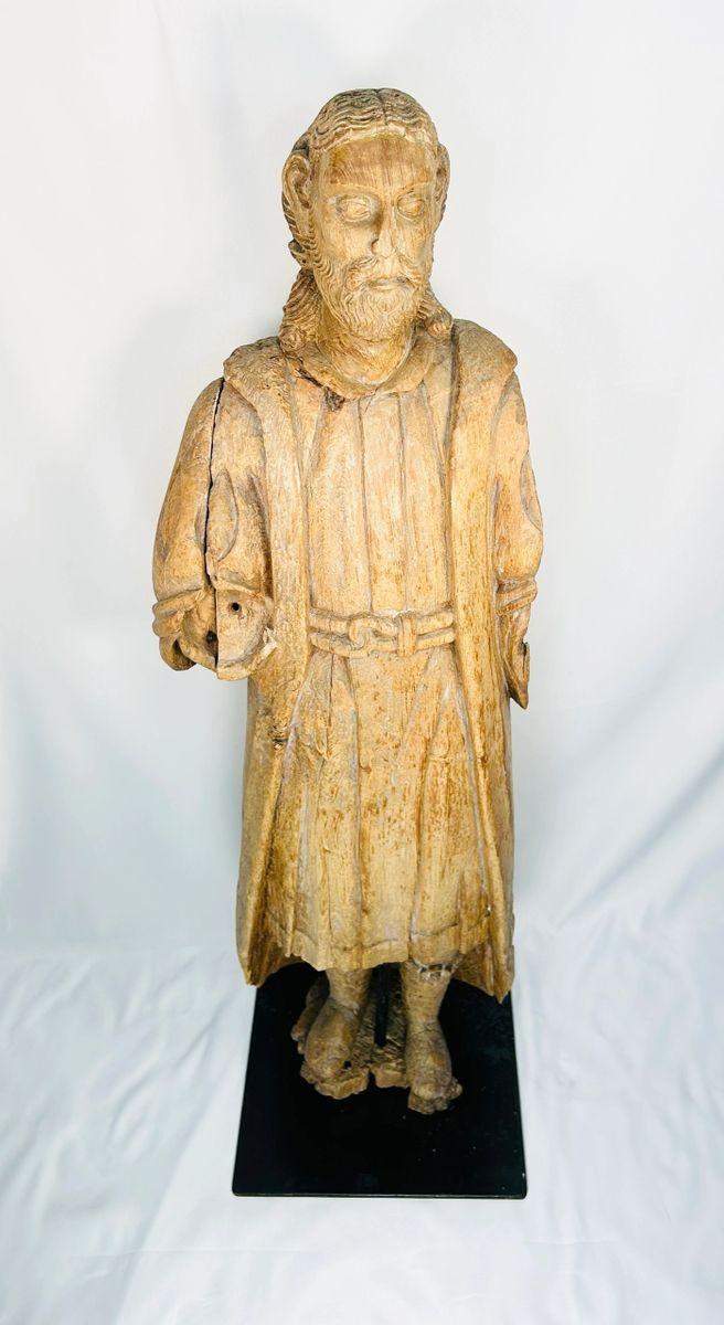 Antique Spanish Colonial wooden Santo statue depicting a standing saint with detailed robes and facial features, mounted on a black display base, 18th–19th century.