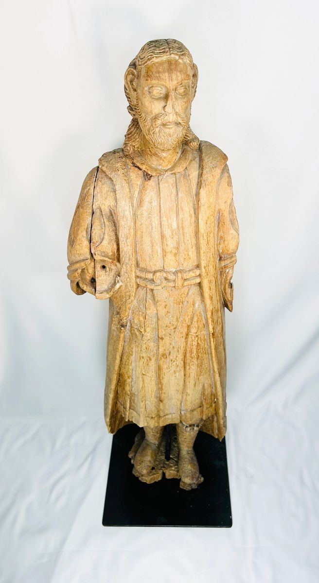 Antique Spanish Colonial wooden Santo statue depicting a standing saint with detailed robes and facial features, mounted on a black display base, 18th–19th century.