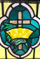 Early 20th-century stained glass artwork, cross and crown design in amber, green, and pink glass, framed in wood, 16x16 in.