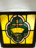 Stained glass panel featuring a cross and crown in amber, green, and pink, early 20th-century, framed in wood, 16 by 16 inches.