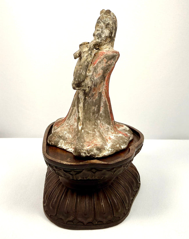 Chinese terracotta funerary sculpture depicting a seated female performer with flowing garments and a traditional pan flute.