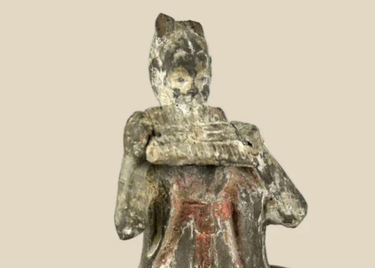 Tang Dynasty terracotta figure of a seated female court musician playing a pan flute, traces of red and white pigments, displayed on a carved wooden stand, 7th–9th century China.