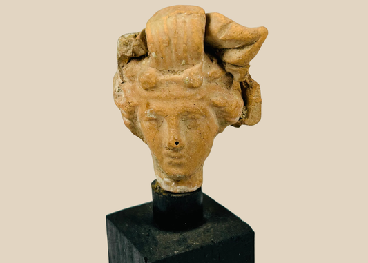 Ancient terracotta head fragment from the Greco-Roman world, circa 4th–1st Century BCE, showing naturalistic facial features and elaborate hairstyle, mounted on a modern black display base, Hellenistic and classical artistic style.