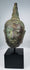 Bronze Buddha head with tightly modeled curls and elongated facial features
