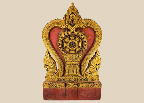 Thai Buddhist shrine panel carved from teakwood, gilded over red lacquer, featuring central dharmachakra and twin naga serpents, late 19th century, Rattanakosin/Lanna tradition, 24.5 x 15 inches