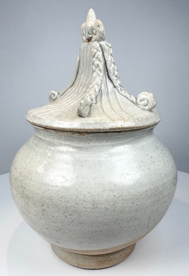 Thai Sawankhalok covered jar with rounded globular body, pale gray-white glaze, and ornate pointed lid.