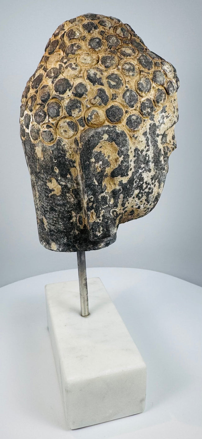 Southeast Asian Buddhist stone sculpture with serene face, aged patina and pigment traces
