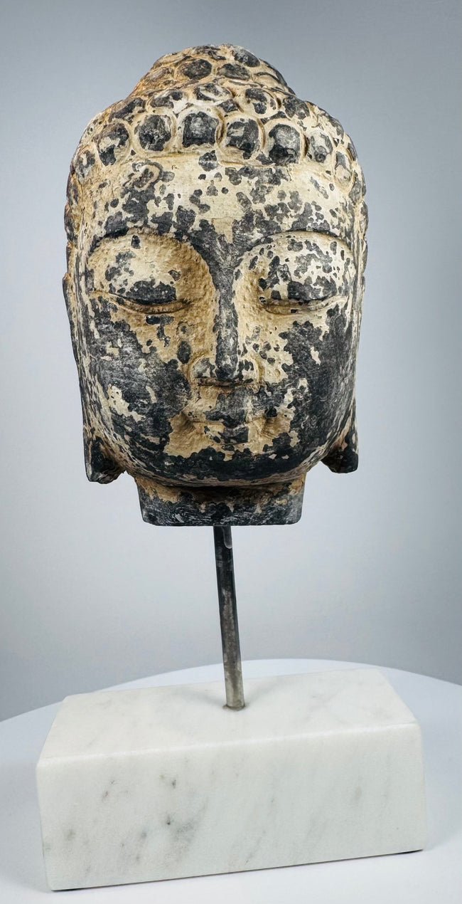 Antique Southeast Asian religious sculpture featuring a hand-carved stone Buddha head