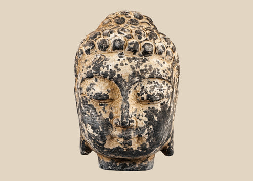 Antique carved stone Buddha head from Southeast Asia, likely Thailand or Cambodia, 18th–19th Century. Features serene meditative expression, curled hair, and traces of original pigments. Mounted on a marble base, reflecting Buddhist artistry, spiritual symbolism, and historical craftsmanship of the region.