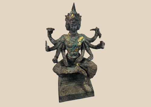 Four-faced, eight-armed Thai bronze Phra Phrom figure with a dark patina, traces of gilding and a tiered pedestal against a warm ivory background.