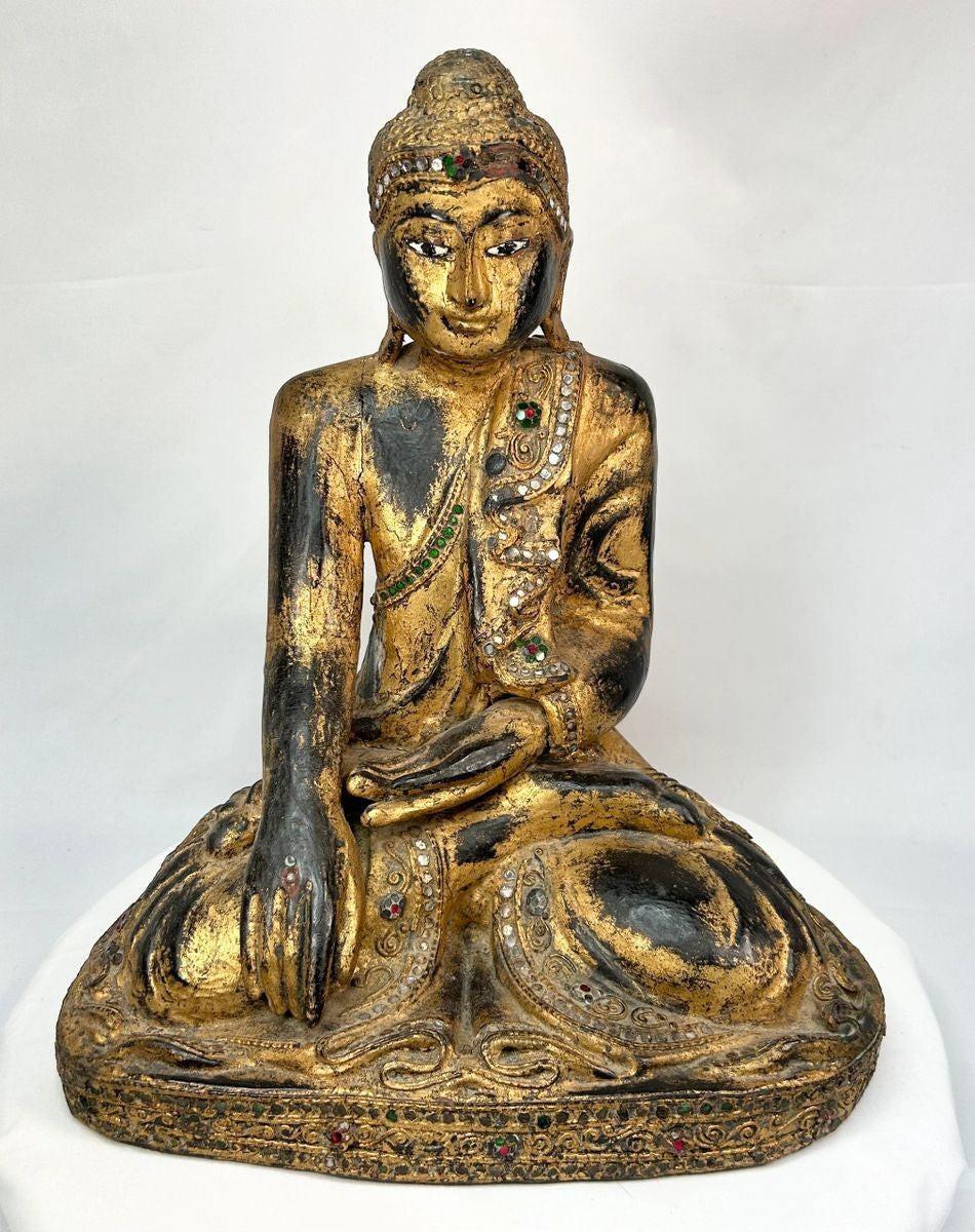 Hand-carved wooden Thai Buddha statue with gilt paint and colorful glass inlays, seated in Bhumisparsha Mudra, symbolizing enlightenment, circa 19th–early 20th century.
