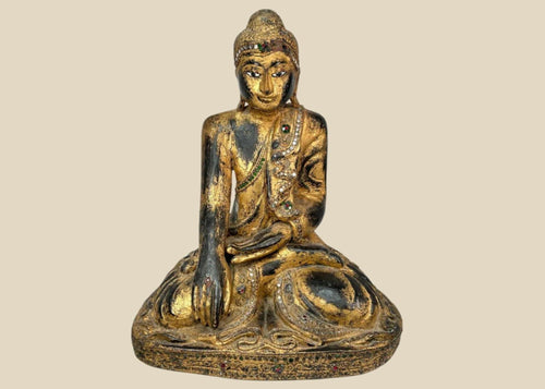 Hand-carved wooden Thai Buddha statue with gilt paint and colorful glass inlays, seated in Bhumisparsha Mudra, symbolizing enlightenment, circa 19th–early 20th century.