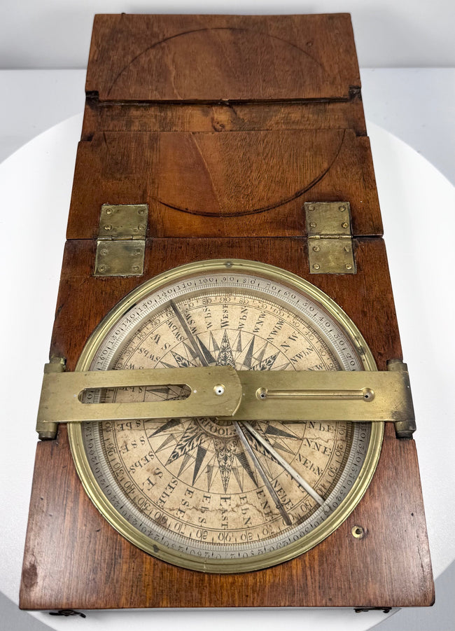 Open Thomas Jones surveying instrument with one brass alidade arm extending across the silvered compass dial.