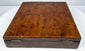 Closed British surveying compass case with central brass-colored lock plate, beveled edge, and naturally aged walnut finish.