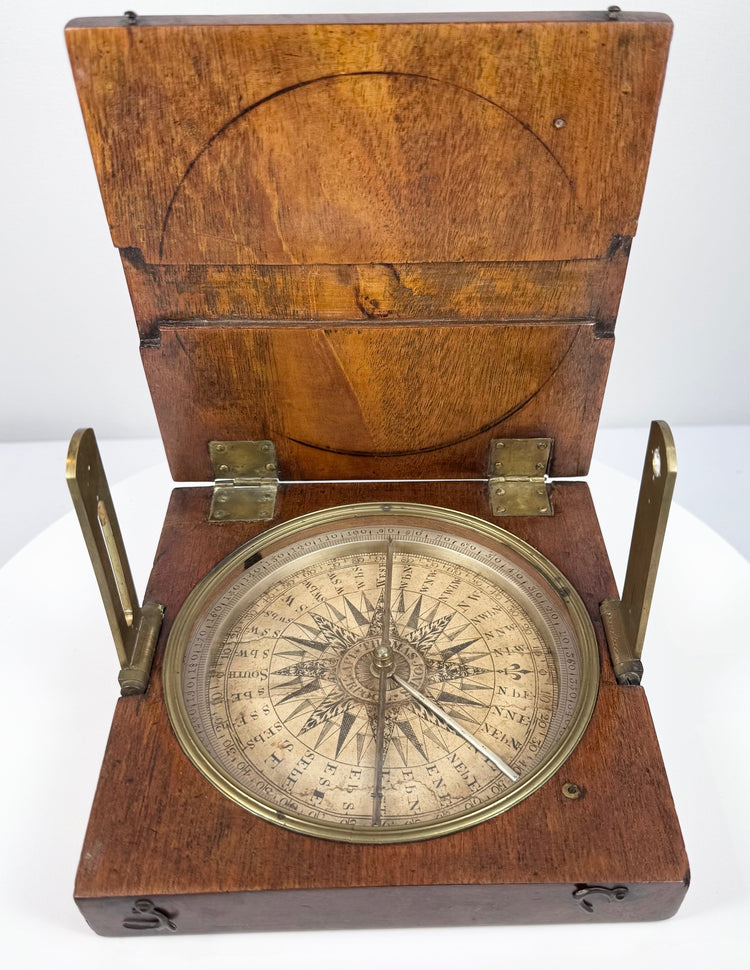 Top-down photograph of the open alidade compass highlighting the silvered degree scale, magnetic needle, and brass sighting components.