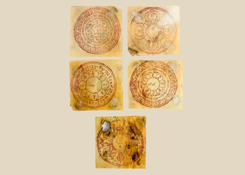 Five circular Tibetan astrological yantras hand-printed in red ink on traditional handmade paper, featuring lotus petals, Eight Auspicious Symbols, and yin-yang motifs, mounted in a modern acrylic display panel, circa 1800s–early 1900s, Tibet/Himalayan Plateau.