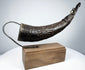 Angled view of a Tibetan carved horn ritual implement with decorative body motifs and opening for ritual use.