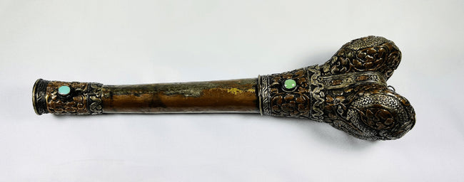 Opposite side of Tibetan human-femur kangling showing two turquoise insets, ornate metalwork and aged patina