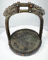 Antique bronze stirrup from the Himalayan region with pierced arch, decorative inlays, and heavy verdigris oxidation.