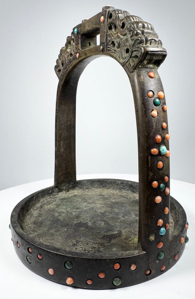 Ornate Himalayan bronze stirrup with pierced latticework, colorful stone inlays, and richly aged green-brown patina.