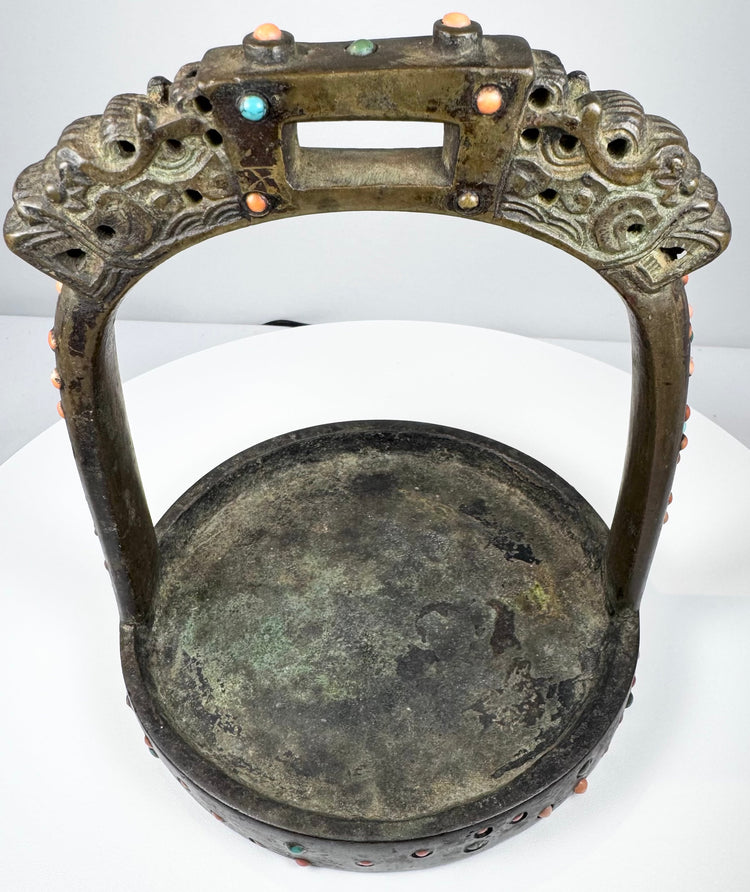 Historic Mongolian or Tibetan stirrup with dark bronze patina, green oxidation, and richly ornamented ceremonial surface.