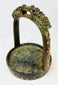Detail shot showing textured bronze surface and colorful inlay on Mongolian saddle stirrup.