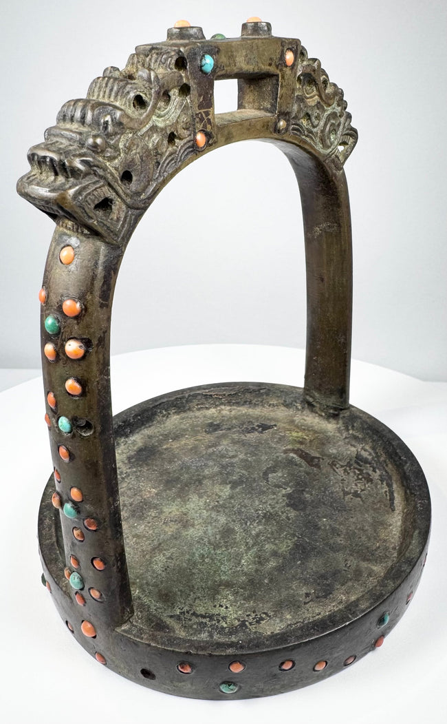 Decorative 18th–19th century bronze stirrup with lattice-pattern arch, saddle strap loop, and surviving colored stone inlays.