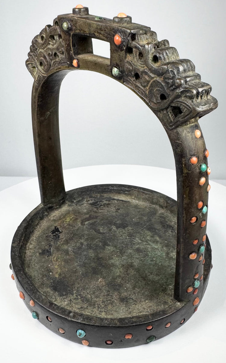 18th–19th century Mongolian or Tibetan bronze stirrup with dragon-head terminals, turquoise, coral, and glass inlays.
